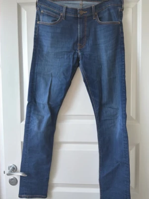 Blå jeans från Lee (W33,L32) - Säljer ett par klassiska blå jeans från Lee med raka ben och snygga kontrastsömmar. Storlek (W33,L32)