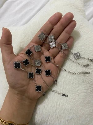 Silverfärgat armband med svarta bärplockare 18+5cm 1 för 120kr - Snyggt armband i silverfärg hängen i svart och dekorerade med små pärlor. Armbandet har tunna kedjor och detaljerade blommönster på vissa hängen. Perfekt accessoar för att lyfta din stil.