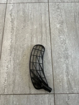 Svart unilite blad i pp titan  - Säljer helt nytt svart innebandyblad i plast med rutmönster och böjd form. Perfekt för dig som vill byta blad på din klubba eller testa något nytt på planen. Passar de flesta standardklubbor och är lätt att montera.