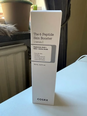 COSRX The 6 Peptide Skin Booster - Serum från COSRX med hyaluronsyra, NAG och aminosyror. Ger jämn hudton, återfuktar och förbättrar hudens struktur. Kommer i en stilren vit förpackning på 150 ml. Perfekt för dig som vill ha glow och vård i ett steg. Oöppnad, ny och skickas i originalförpackning.