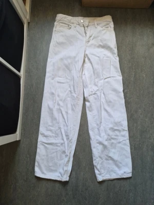 Vita baggy jeans med medelhögmidja - Säljer ett par vita jeans med baggy passform. På gina tricots hemsida står det att dessa är lågmidjade men de är lite medelmidja. Klassisk femficksmodell med dragkedja och knapp framtill. 