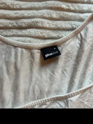 Vit linnetopp från Gina Tricot - Säljer en enkel och stilren vit linnetopp från Gina Tricot. Toppen har breda axelband och en fyrkantig ringning som ger en modern look. Perfekt att matcha med jeans eller kjol för en clean outfit.