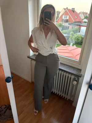 Mullvadsfärgade kostymbyxor  - Snygga  kostymbyxor med hög midja samt resår. Byxorna har diskreta sidfickor och stängs med dragkedja och knapp. Perfekta för en clean och stilren look. Materialet ser ut att vara en mjuk och lätt vävd textil. Använda en gång. Nypris 400kr.