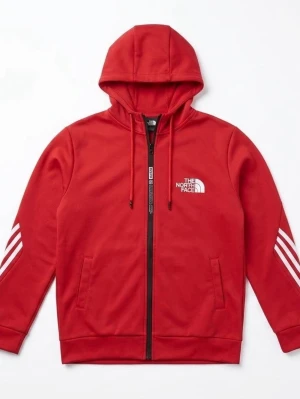 Röd hoodie från The North Face - Snygg röd hoodie med dragkedja från The North Face. Den har vit logga på bröstet, vita ränder på ärmarna och två fickor framtill. Tillverkad i mjukt material och har justerbar huva med snören. Perfekt för en avslappnad streetwear-look.