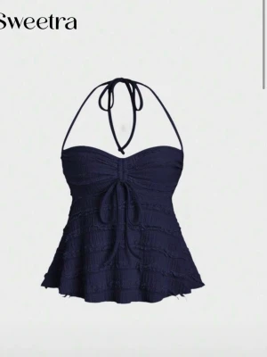 Mörkblå sommar topp - Supersnygg sommar topp. halterneck och volangdetaljer. Toppen har en söt knytning framtill och lätt utställd kjoldel som ger en feminin siluett. Tillverkad i stretchigt material som sitter bekvämt och formar sig efter kroppen.