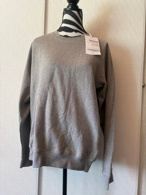 Grå sweatshirt från Neutral - En stilren grå sweatshirt från Neutral i mjukt material. Tröjan har rund halsringning, långa ärmar och ribbade muddar vid ärmslut och nederkant. Tillverkad av ekologisk bomull och har en enkel, klassisk design utan tryck eller huva.