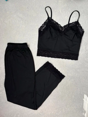 Svart spetsigt underklädesset - Säljer ett svart underklädesset / pyjamas i storlek M med linne och byxa. Linnet har tunna axelband, v-ringning och spetsdetaljer längs urringning och nederkant. Byxorna har resår i midjan och spets vid benslut. Lappen är bortklippt men kommer troligtvis från Shein eller liknande! 
