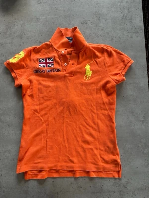 Pikétröja från Ralph Lauren. Great Britain  - Mycket bra skick. Slim fit. Bredd armhåla till armhåla: 44 cm. Längd: 65 cm. Säljer för att jag inte tycker om den längre. Skriv om du har frågor! 