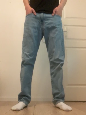 Ljusblå jeans från Levi's 502 - Säljer ett par klassiska 502 ljusblå jeans från Levi's med rak passform och femficksdesign. Jeansen har normal midja och är tillverkade i slitstark denim. Perfekta för dig som gillar en tidlös och avslappnad stil.