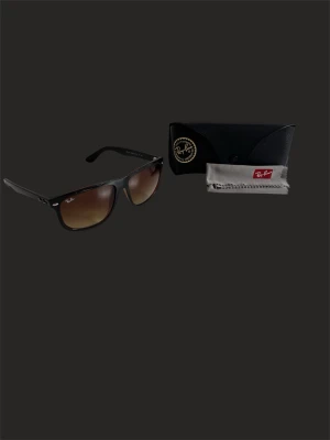 Ray-Ban svarta solglasögon  - Klassiska svarta Ray-Ban solglasögon med bruna tonade glas. Snygg och tidlös design med Ray-Ban-logga på bågen. Kommer med originalfodral och putsduk. Perfekta för soliga dagar och ger en cool vibe till din outfit.