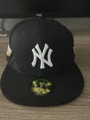 New Era Yankees World Series keps - Snygg svart keps från New Era med New York Yankees-logga framtill och broderad 'World Series 2024' patch på sidan. Klassisk rak skärm och justerbar passform. Perfekt för dig som gillar streetwear och baseballstil.