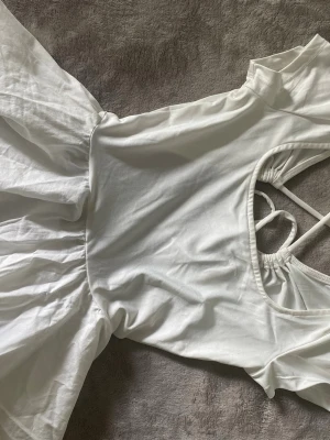 Öppenrygg peplum topp vit - Köpt på hm. Använt 2-3 gånger. Sicksack och knut bak. Öppen rygg och volang nertill.