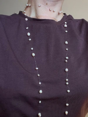 Långt Halsband med Ljusrosa Sötvattenspärlor - Långt halsband i 2000-tals stil med sötvattenspärlor på tålig genomskinlig tråd. Kan viras runt halsen på olika sätt. 121 cm långt. 