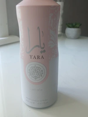 ! DEOSPRAY ! MYCKET KVAR - Yara parfym spray från Lattafa i en elegant rosa och vit metallflaska med dekorativa mönster och arabiska bokstäver. Flaskan rymmer 200 ml och har en feminin, modern design som sticker ut på hyllan.