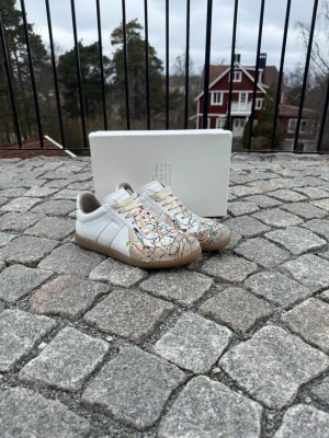 Maison Margiela Skor - Säljer dessa sjukt snygga vita Maison Margiela skor med Paint Splatter. Storlek 41, men stora i storleken så ungefär 42. Ca 26.5cm på insidan. Nypris på dessa är 8000kr. Självklart äkta. Box ingår. Hör av vid frågor eller funderingar! Kan gå ner i pris vid snabb äffär. 🙌🏻💯🍾