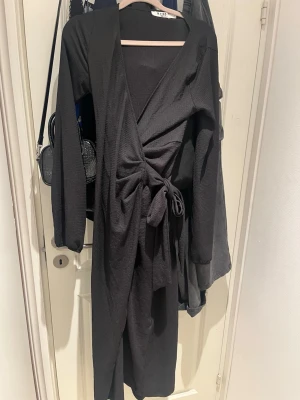 Svart wrap midiklänning nakd - Fins svart vadlång omlottklänning med ballong ärmar och lätt V-ringning. Säljes i stl S.💕