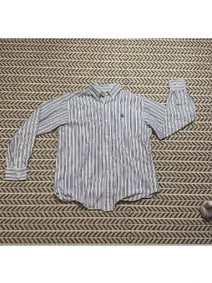 Randig skjorta från Ralph Lauren - Klassisk skjorta från Ralph Lauren med blå och vita ränder. Skjortan har lång ärm, knappar framtill och den ikoniska broderade loggan på bröstet. Tillverkad i bomull och har en avslappnad passform. Perfekt för en stilren och tidlös look.