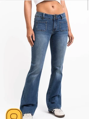 Blå bootcut jeans med fickor fram - Har bara haft på mig dem en gång. Säljer ett par blå bootcut jeans med två stora fickor framtill och utsvängda ben. Jeansen har en klassisk midja och stängs med dragkedja och knapp. Perfekta för en avslappnad och trendig look.