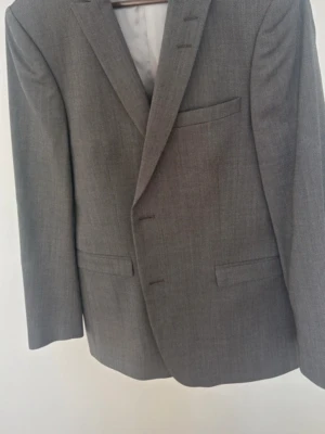 Grå kostym med kavaj och byxor. Tiger of Sweden  - Snygg grå kostym med klassisk kavaj och matchande byxor från Tiger of Sweden . Kavajen har smala slag, tre fickor fram och knäppning med två knappar. Byxorna är raka och har pressveck. Perfekt för dig som vill ha en stilren och tidlös look.