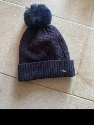 Blå mössa  - Har använts i stall innan men knappt använd Tvättas inann den skickas  Har mjuk o varm insida  Man kan ta av bollen på mössan o sätta på med en knapp