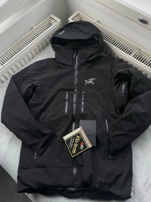 Svart Arc’teyx jacka  - Hejsan! Säljer mina jacka som inte kommer till användning, den har en liten defekt och de är att dragkedjan på fickan höger sida är trasig men annars är den som ny. Storlek medium i herr storlek. Jag vet inte om den är äkta eller inte så räkna med att den inte är det och det är därför säljer jag den för billigt gemnfört med en äkta. Köpte för 4300kr och säljer för 1800kr. Hör av er om det nåt några frågor☺️ 