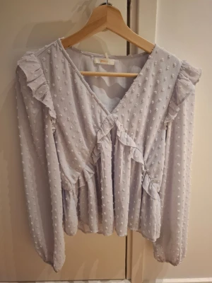 Ljusvblå blus med volanger - Supersöt blus från Gina Tricot med volangdetaljer och prickig struktur. Blusen har v-ringning och långa ärmar. Skriv privat om ni undrar något. Priset går eventuellt att diskutera❤️