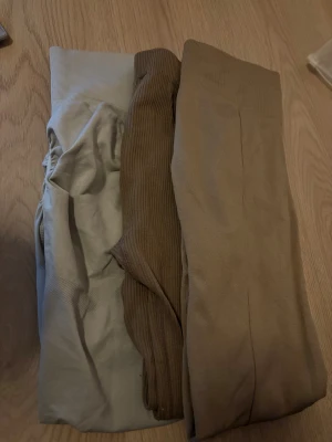 3-pack leggings i beige och brunt - Säljer ett 3-pack leggings i olika beige och bruna nyanser. Alla leggings har hög midja och bred mudd upptill för extra komfort. Materialet ser ut att vara stretchigt och mjukt, perfekt för en avslappnad look. Inga synliga loggor eller märken.