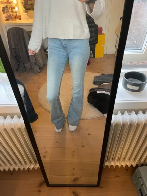 Ljusblå bootcut jeans - Säljer ett par ljusblå bootcut jeans med hög midja och klassisk femficksdesign. Jeansen har en snygg tvättad look och är tillverkade i ett mjukt denimtyg som sitter bekvämt. Perfekta för dig som gillar en retroinspirerad stil.