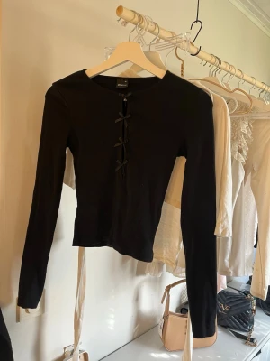 Svart långärmad topp med snörning - En långarmad fin tröja med rosetter i mitten, säljer pågrund av ej kommer till användning 🥰🥰🥰🥰