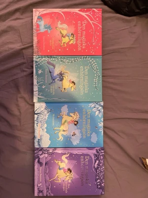 Den magiska enhörningsön bokserie - Fyra böcker ur serien 'Den magiska enhörningsön' med färgglada omslag i rött, grönt, blått och lila. Böckerna har fantasifulla illustrationer av enhörningar och magiska landskap. Perfekt för dig som gillar äventyr och magi. Författare: Zanna Davidson