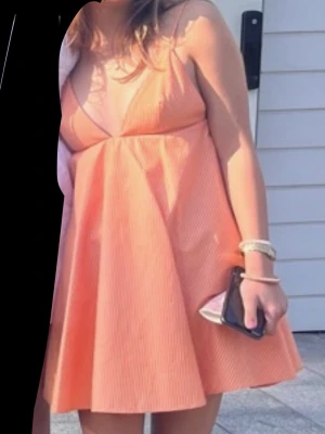 Sommar klänning❤️🌷🌸 - Supersöt kort klänning i orange med tunna vita ränder och omlott-v-ringning. Klänningen har smala axelband och en luftig, A-linjeformad passform som ger en skön sommarkänsla. Perfekt för varma dagar och snygg att styla med smycken eller sneakers. Den har bara används en gång❤️