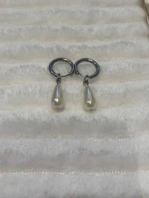 Silvriga hoops med droppformade pärlor i rostfritt stål💍 - Vi är ett UF företag som tillverkar och säljer örhängen och armband. Dessa örhängen är stilrena med silvriga hoops och droppformade vita pärlor som hänger ner. Perfekta för dig som gillar en enkel men elegant look. Materialet är rostfritt stål Vi säljer även örghängena på sista bilden och alla designer finns i både guld och silver🌸