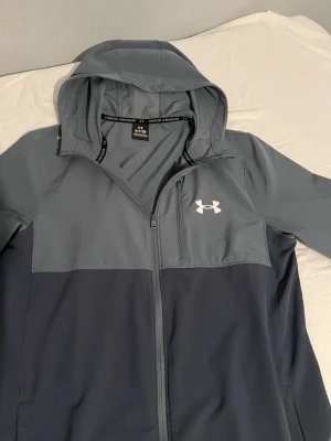 Grå vindjacka från Under Armour - tja en under armour jacka som är i mycket god skick ( 9/10) den är använd några gng men ligger bara i garderoben. Hör av er om ni blir intresserade 🙏🏻