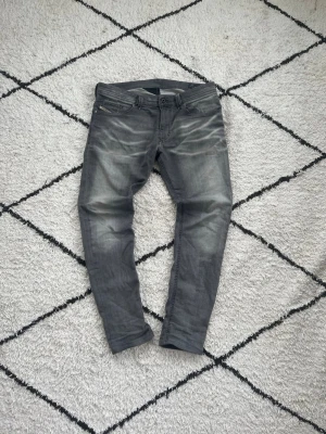 Diesel jeans - Diesel jeans i superfint skick – storlek 32 Säljer ett par riktigt snygga Diesel jeans i grå/svart tonad tvätt. Jeansen är i mycket bra skick – nästan som nya! Inga hål, inga slitna partier, färgen är fin och jämn. Klassisk slim/tapered passform som sitter grymt bra.