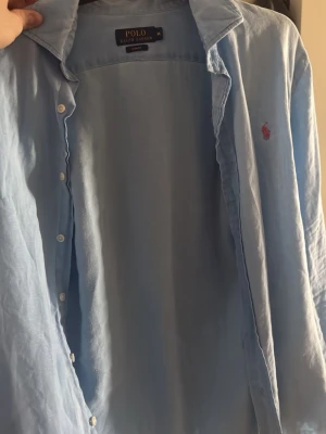 Ljusblå linneskjorta Polo Ralph Lauren - Säljer en ljusblå linneskjorta från Polo Ralph Lauren i slim fit-modell/ storlek M, pris kan diskuteras, skjortan har även bara används 2 gånger!