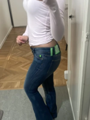 Blå bootcut jeans med låg midja - Säljer ett par blå bootcut jeans med låg  midja och klassiska fickor bak. Jeansen har en snygg tvätt och är tillverkade i denim med lätt stretch. Perfekta för dig som gillar en retroinspirerad look och vill ha ett par jeans som sitter tajt upptill och släpper vid benen.