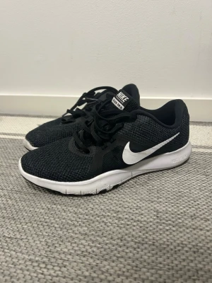 Svarta Nike Flex sneakers - Snygga svarta Nike Flex sneakers (RIKTIGA) med vit sula och klassisk vit swoosh på sidan. Ovandelen är i meshmaterial som andas och har svarta skosnören. Perfekta för dig som gillar sportig och clean stil. 