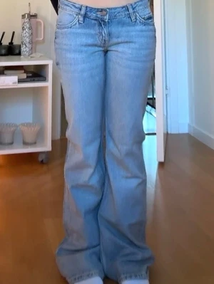 Ljusblå bootcut jeans - Säljer ett par ljusblå bootcut jeans med klassisk femficksdesign och normal midja. Jeansen har en avslappnad passform och är tillverkade i denim med lätt tvättad look. Perfekta för en trendig och avslappnad stil.