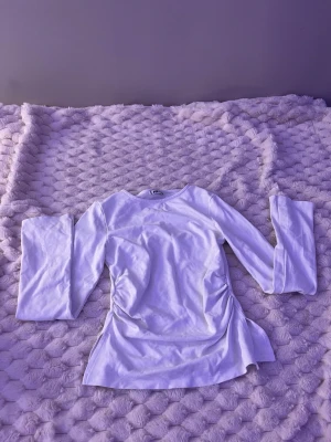 Vit långärmad topp från Gina Tricot - Säljer en enkel och stilren vit långärmad topp från Gina Tricot. Toppen har rund halsringning och är tillverkad i mjuk bomull. Passar perfekt till jeans eller kjol för en clean look.