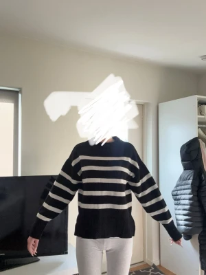 Svartvit randig stickad tröja - Säljer en oversized stickad tröja med breda svarta och vita horisontella ränder. Tröjan har långa ärmar, ribbade muddar och en högre rund halsringning. Perfekt för dig som gillar en avslappnad och trendig look.