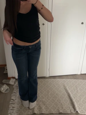 Mörkblå bootcut jeans - Säljer ett par mörkblå bootcut jeans med låg midja och klassisk femficksdesign. Jeansen har en snygg tvätt och sitter tight upptill med utsvängda ben. Perfekta för dig som gillar en retro och avslappnad stil. Storlek 164 men passar mig perfekt som S!!!💞💞💞 Endast använd ett fåtal gånger 