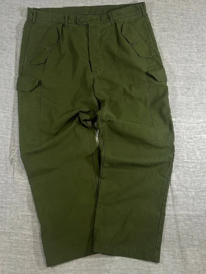 Military cargo pants olive green baggy fit wide leg utility - Clean military cargo pants in a perfect olive tone. Heavy-duty feel with a relaxed baggy fit and wide leg. Proper utility vibe with big cargo pockets – easy to style with boots or sneakers.  Size: C56 (fits W38–W40) Waist: 49 cm Rise: 30 cm Thigh: 37 cm Knee: 31 cm Foot: 23 cm Full Length: 101 cm  Good used condition.