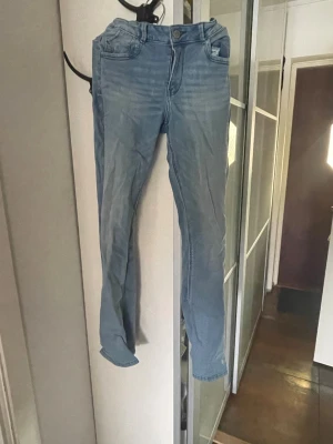 Ljusblå slim fit jeans - Säljer ett par ljusblå flared jeans med  normalhög midja. Jeansen har en snygg tvättad look och raka ben. Perfekta för dig som gillar en enkel och stilren stil. Och ett snyggt stjärn mönster i finckorna 