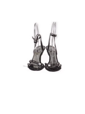 Svarta stilettosandaler med remmar - Säljer ett par svarta sandaler med smala stilettklackar och tunna remmar. Skorna har dekorativa detaljer framtill och justerbart spänne vid ankeln. Materialet ser ut att vara glansigt, troligen konstläder eller lack. Perfekta för dig som vill ha en edgy och elegant look.