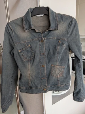 Blå jeansjacka från Promod - Snygg och unik blå jeansjacka från Promod med två bröstfickor och två snedställda fickor framtill. Köpt i Berlin. Nyskick. Jackan har en tidlös design med krage, knappstängning och långa ärmar. Perfekt för en avslappnad och trendig look. Skickar snabbt.