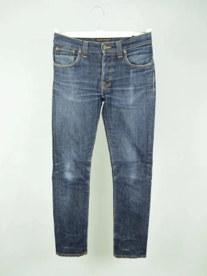 Nudie grim tim  - NUDIE JEANS Storlek : 30/32 (SE MÅTT) Modell : Grim Tim Mått : A = 38CM - B = 98CM - C = 15,5CM Användning : Jeansen är i ett väldigt fint skick (pris är inte rispat i sten)