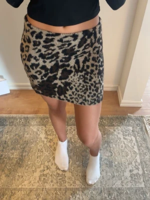 Leopardmönstrad kortkjol från H&M - Säljer en snygg leopardmönstrad kortkjol från H&M i beige och svart. Kjolen har en tight passform och är stickad, vilket gör den både mjuk och bekväm. 🤎