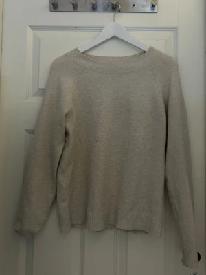 Beige stickad tröja med rund hals - Mysig beige stickad tröja med rund halsringning och långa ärmar. Tröjan har ribbade muddar vid ärmslut och nederkant. 