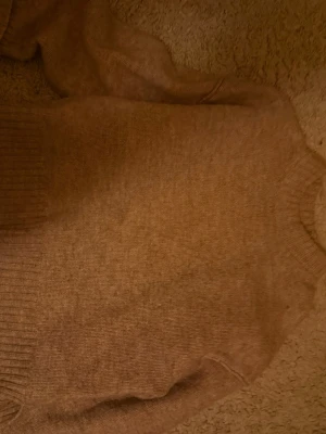 Beige stickad tröja med rund hals - Mysig beige stickad tröja med rund hals och ribbade muddar vid ärmslut och nederkant. Perfekt för lager på lager och enkel att matcha med olika stilar. Tröjan har en klassisk passform och är tillverkad i mjukt material.