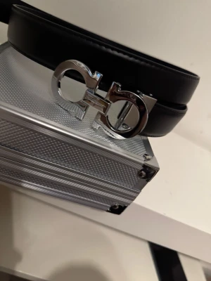 Silver skärp från Salvatore Ferragamo - Snyggt silver skärp från Salvatore Ferragamo med ikoniskt silverfärgat dubbel-Gancio-spänne. Skärpet är gjort i slätt skinn och har en stilren, modern look som passar till många outfits.